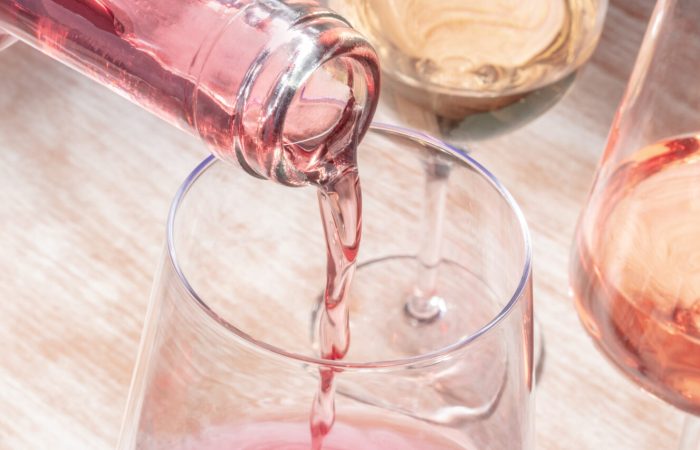 Rose wine pouring panorama with various glasses on a wooden table